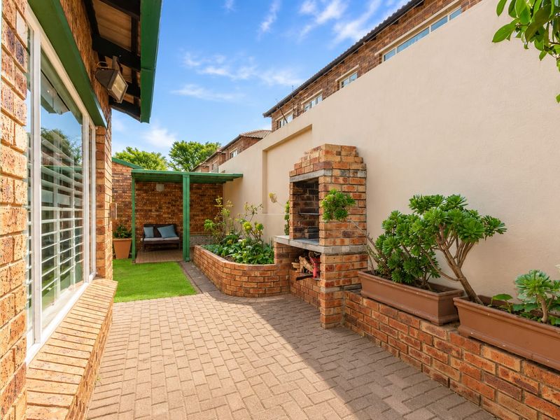 A well-maintained outdoor patio area featuring a built-in brick braai, paved flooring, and integrated brick planter boxes, perfect for outdoor entertaining.