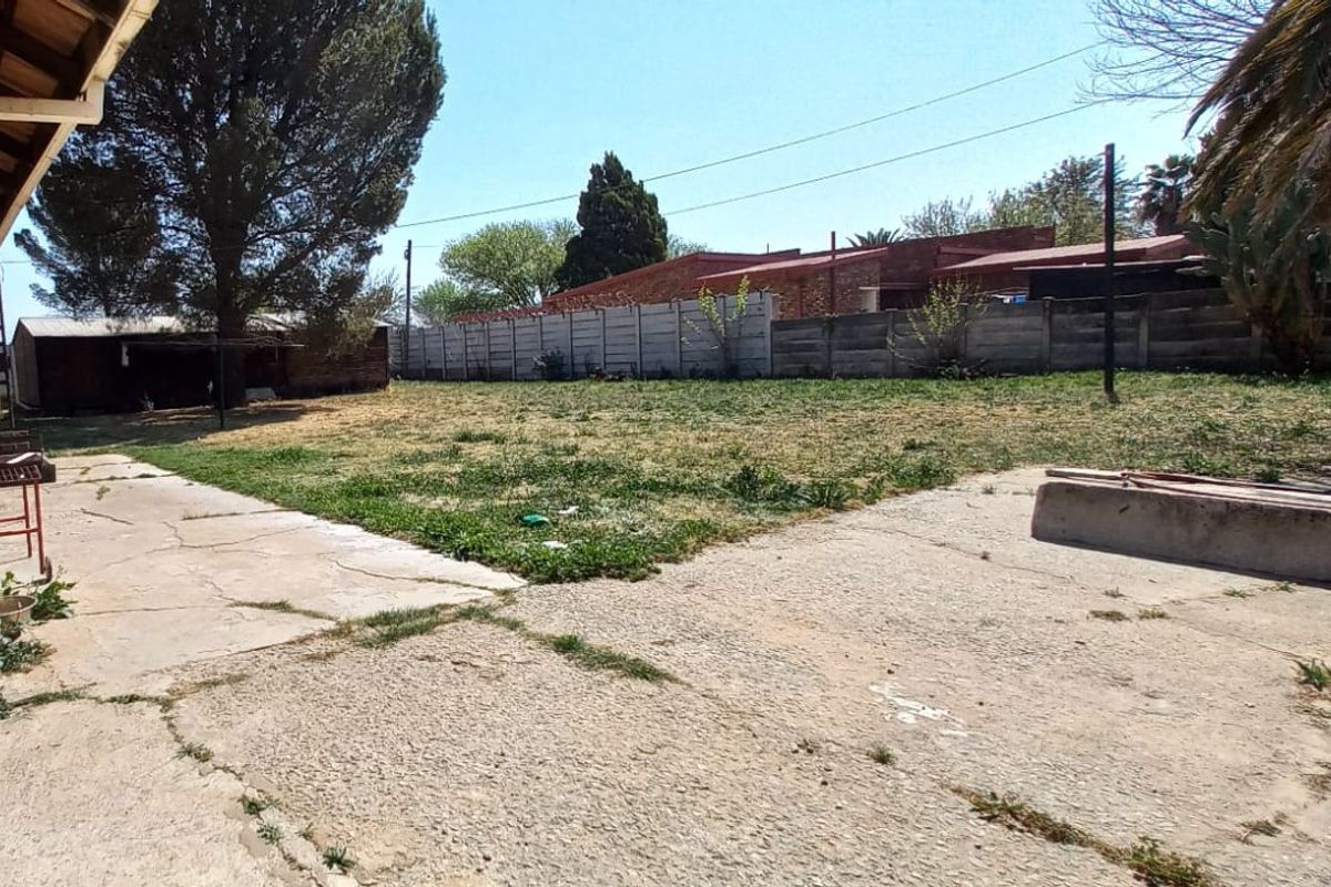 Spacious rear garden featuring a large concrete patio area and precast boundary walling, offering significant potential for landscaping and outdoor entertainment development.