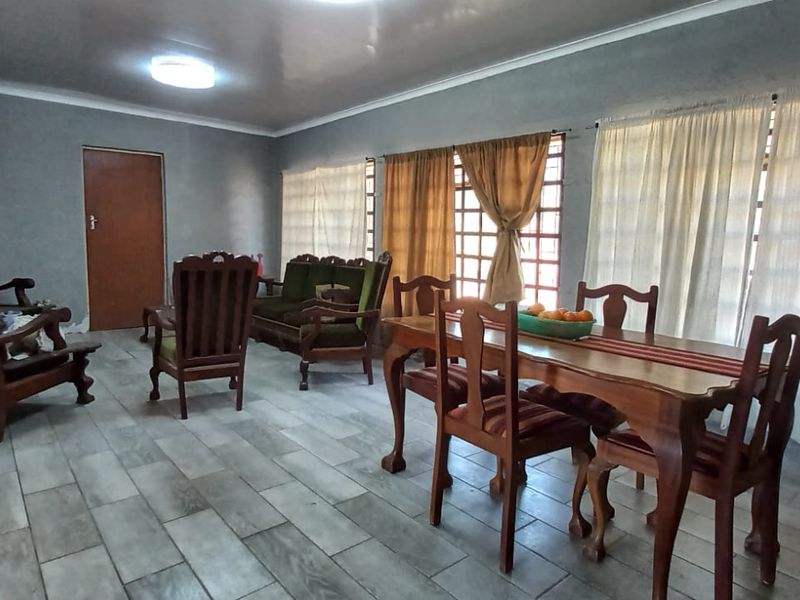 Spacious open-plan living and dining area featuring neutral wall finishes, tiled flooring, and large windows that provide ample natural light.