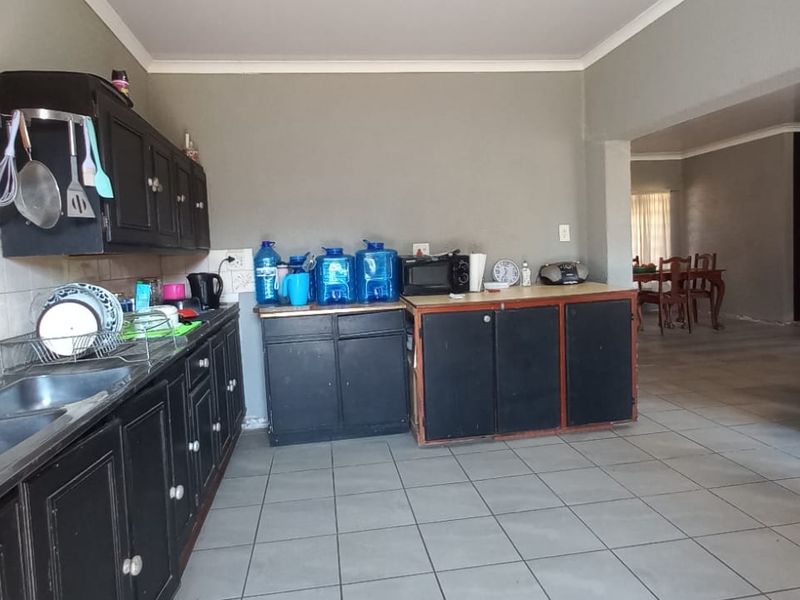 Open plan kitchen and dining area featuring tiled flooring, dark built-in cabinetry, and a double basin sink, offering a functional layout for renovation.
