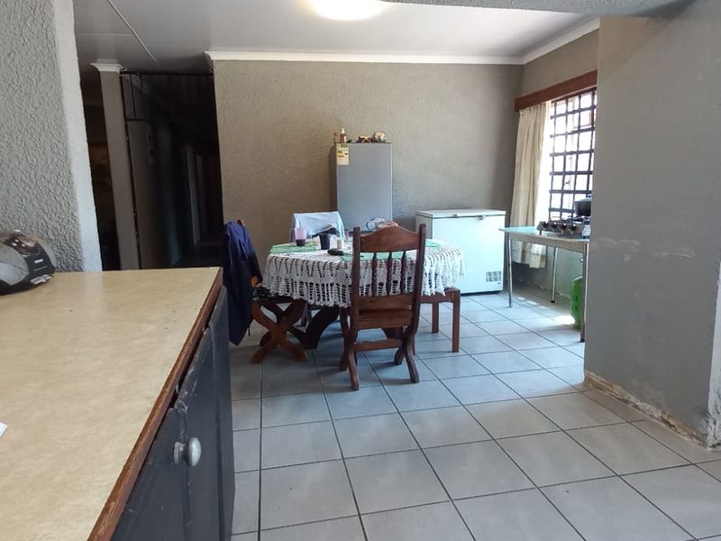 Open plan living and dining area featuring tiled flooring and security bars on windows, requiring cosmetic updates to improve the overall aesthetic.