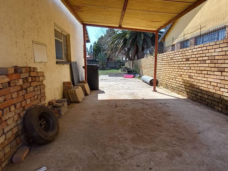 A covered outdoor patio area featuring a concrete floor, metal roofing, and brick boundary walls, offering potential for a functional outdoor entertainment space.
