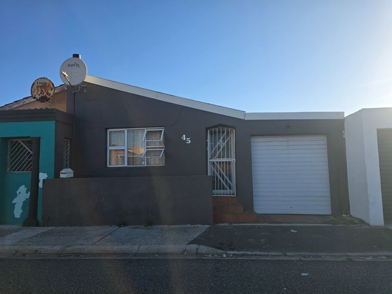 Front elevation of a single-story house featuring a garage, security gate, and dark grey exterior finish.