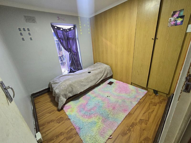 A compact bedroom featuring laminate flooring and built-in wooden cupboards, providing functional storage space.