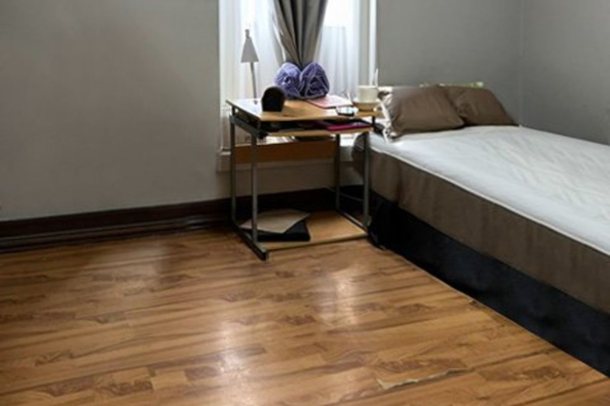 A bedroom featuring laminate flooring, skirting boards, and a window with natural light.