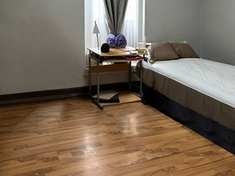 A bedroom featuring laminate flooring, skirting boards, and a window with natural light.