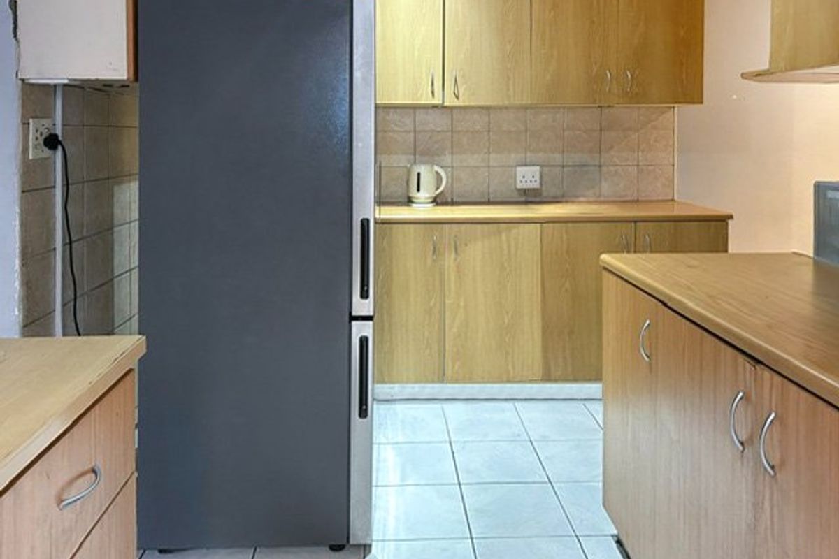 A functional kitchen featuring laminate cabinetry, tiled backsplash, and ceramic floor tiles, offering a practical layout for daily meal preparation.
