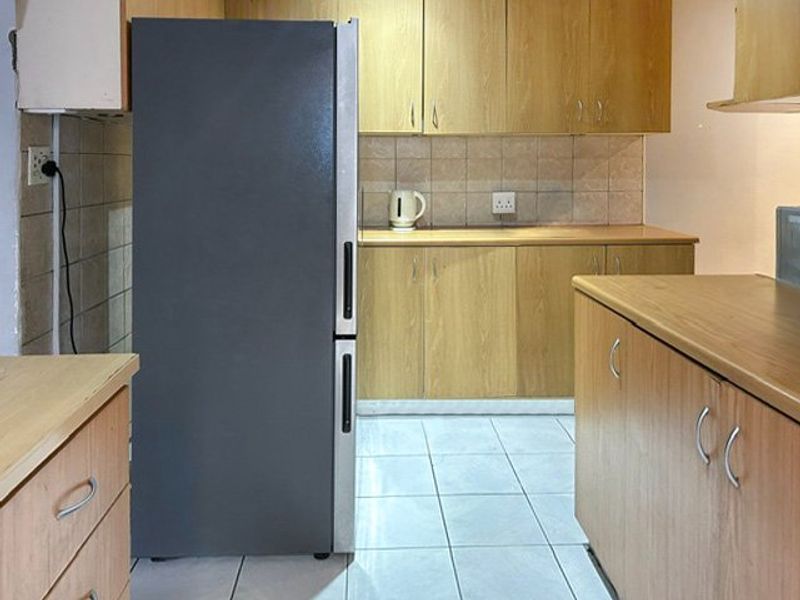 A functional kitchen featuring laminate cabinetry, tiled backsplash, and ceramic floor tiles, offering a practical layout for daily meal preparation.