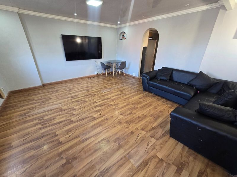 Spacious living room featuring laminate flooring, an arched doorway, and recessed ceiling lighting, offering a neutral base for interior design updates.