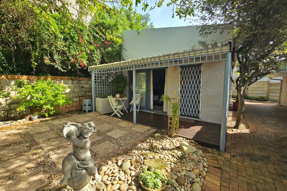 Rear exterior view featuring a covered timber deck patio, paved garden area, and secure access to the main dwelling.