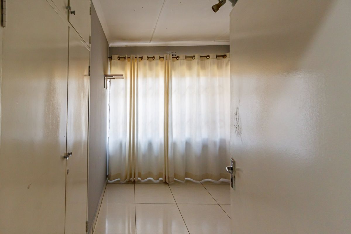 A vacant bedroom featuring tiled flooring and built-in cupboards, offering a neutral canvas ready for personalization.