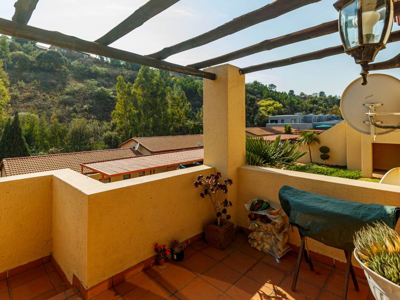 A covered balcony featuring a timber pergola, terracotta tiling, and a masonry balustrade, offering elevated views of the surrounding residential area.