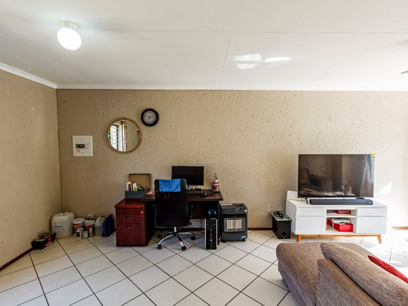 A living area featuring tiled flooring and textured walls, currently utilized as a multi-purpose space with an integrated electrical distribution board.