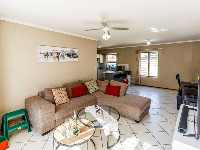 Open-plan living area featuring tiled flooring, a ceiling fan, and a functional kitchen space with a breakfast island.
