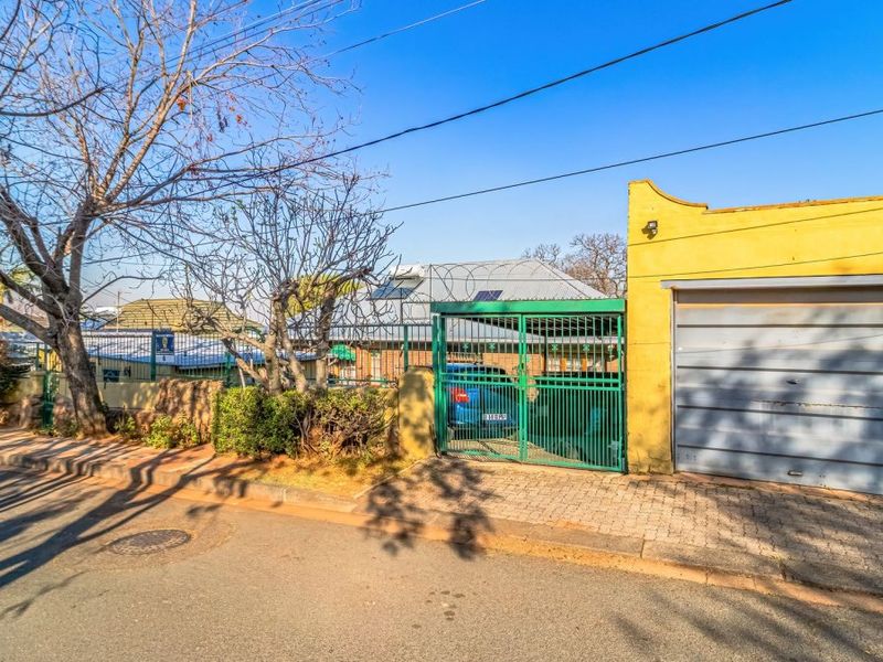 Street view of the property frontage featuring a single garage, paved driveway, and secure metal gate with perimeter fencing.