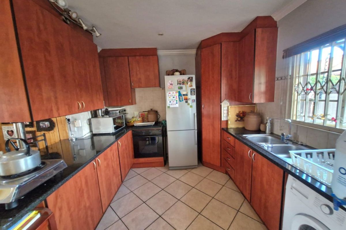 A functional kitchen featuring wood-finish cabinetry, granite countertops, tiled flooring, and integrated appliances, offering a practical layout for daily meal preparation.