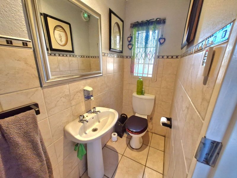 A compact guest bathroom featuring a pedestal basin, toilet, and neutral ceramic tiling throughout.