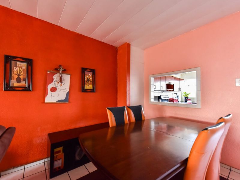 Dining room featuring tiled flooring, a tongue and groove ceiling, and a convenient serving hatch connecting to the kitchen area.