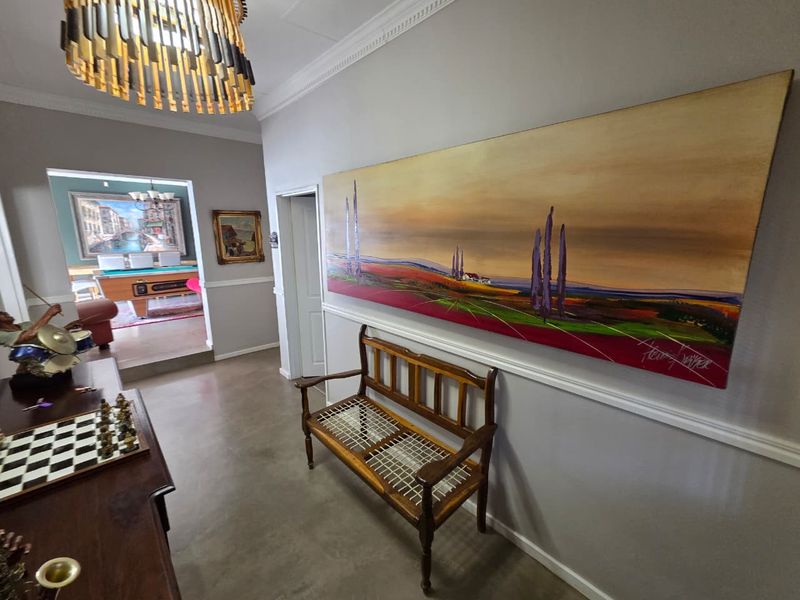 Spacious hallway featuring elegant crown molding, chair rail detailing, and polished concrete flooring, leading into an adjacent living area.