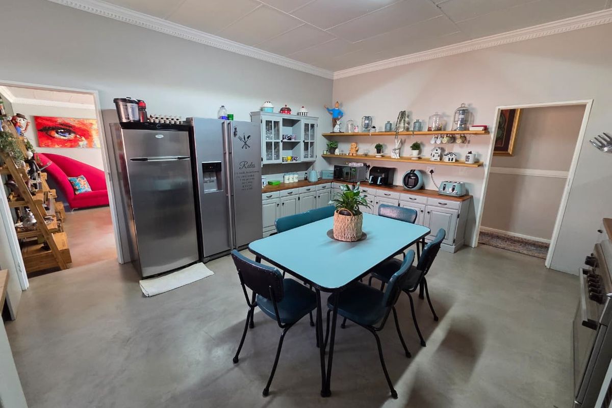 Spacious kitchen featuring concrete flooring, built-in cabinetry, and floating timber shelving, offering a functional layout with ample storage space.