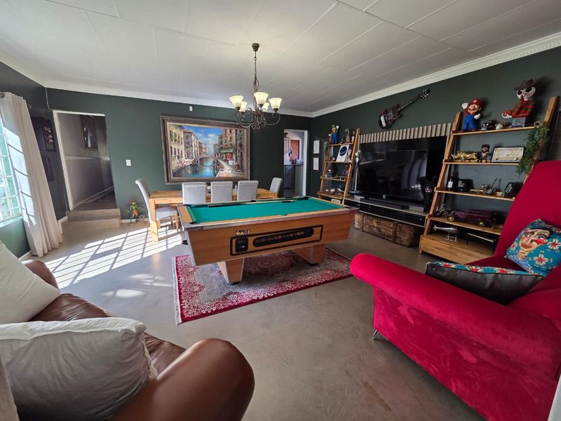 Spacious open-plan living and dining area featuring dark accent walls, tiled flooring, and decorative ceiling cornicing, creating a versatile entertainment space.
