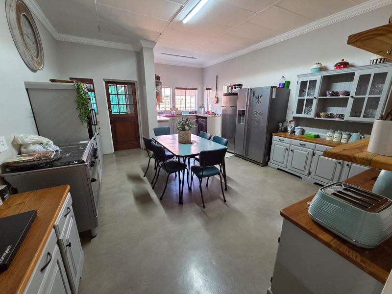 Spacious open-plan kitchen and dining area featuring built-in cabinetry, wooden countertops, and durable concrete flooring with direct access to the exterior.