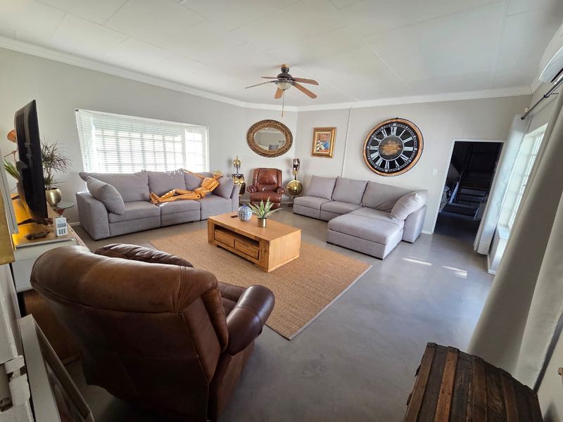 Spacious living room featuring neutral walls, polished concrete flooring, a ceiling fan, and an integrated air conditioning unit.