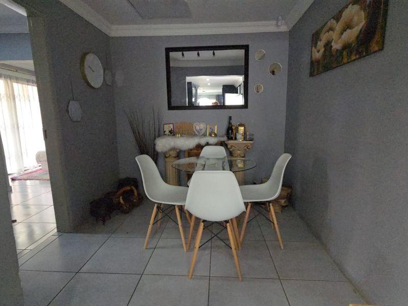 A compact dining area featuring neutral grey walls, tiled flooring, and decorative crown molding, providing a functional space for meals.