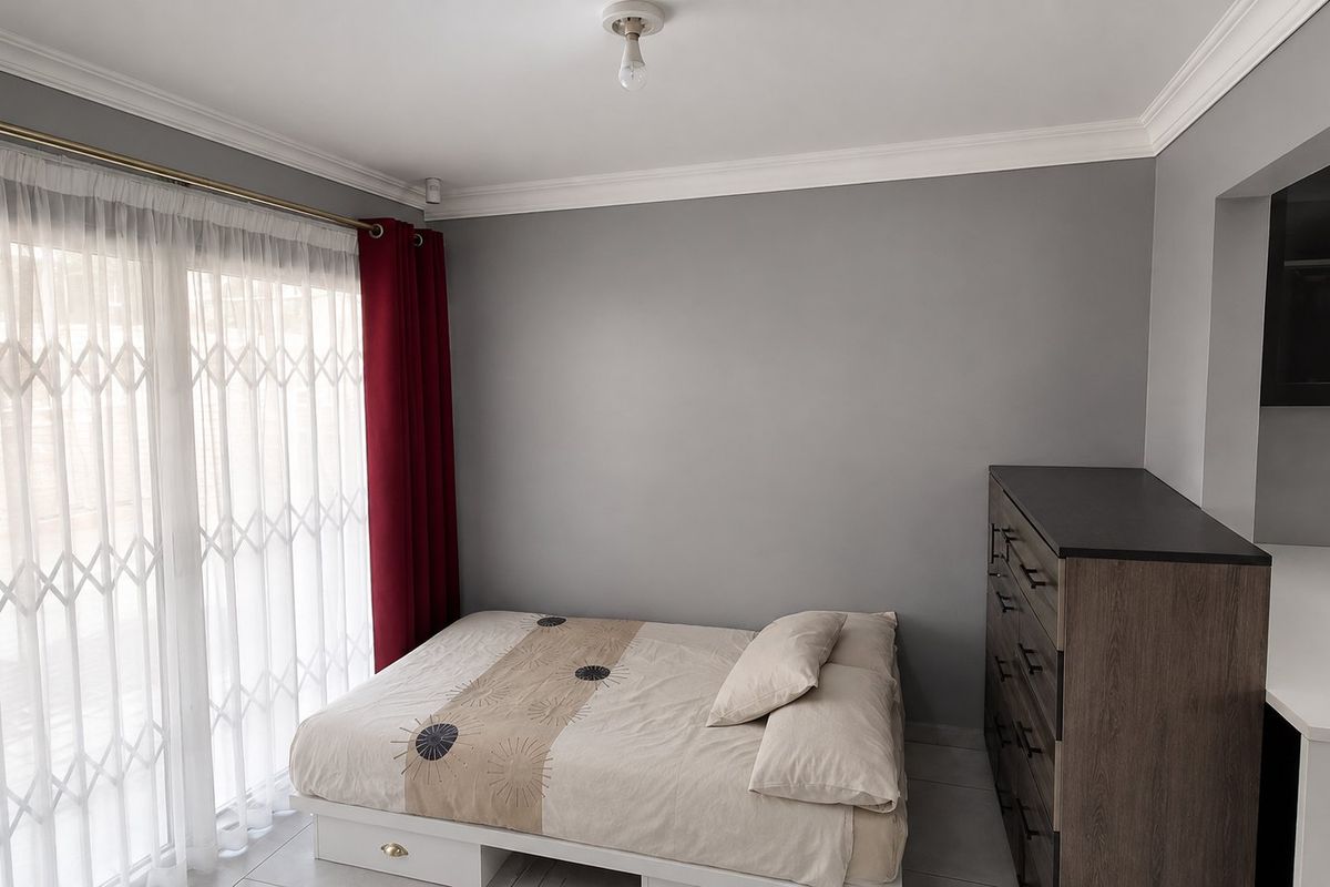 A bedroom featuring grey walls, crown molding, and a sliding glass door with a security gate, providing access to the exterior.