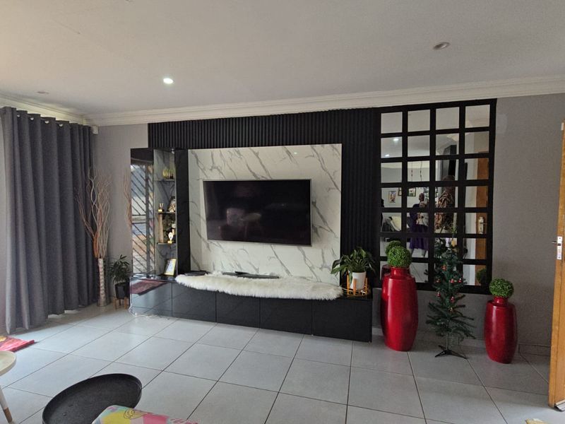 Modern living room featuring a custom built-in media unit with marble-effect paneling, slatted accents, and a decorative grid-pattern mirror wall.