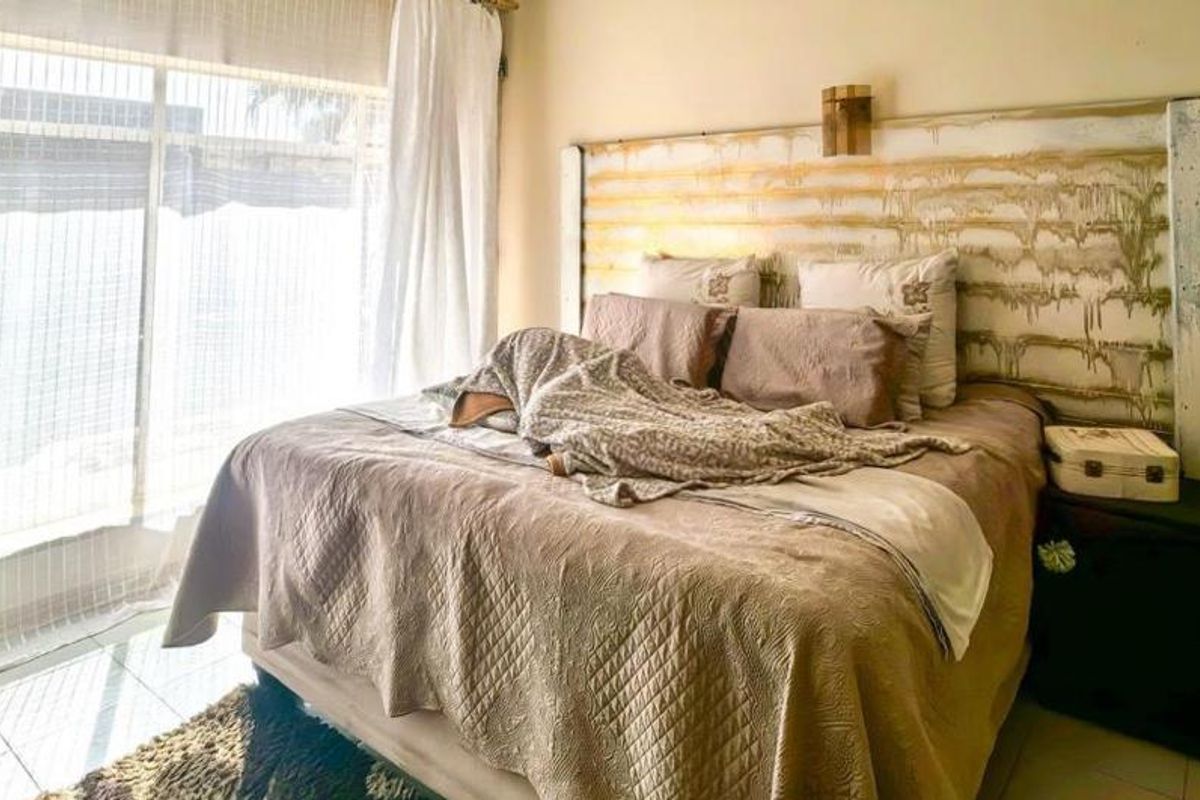 A bedroom featuring tiled flooring and a large sliding glass door that allows for natural light.