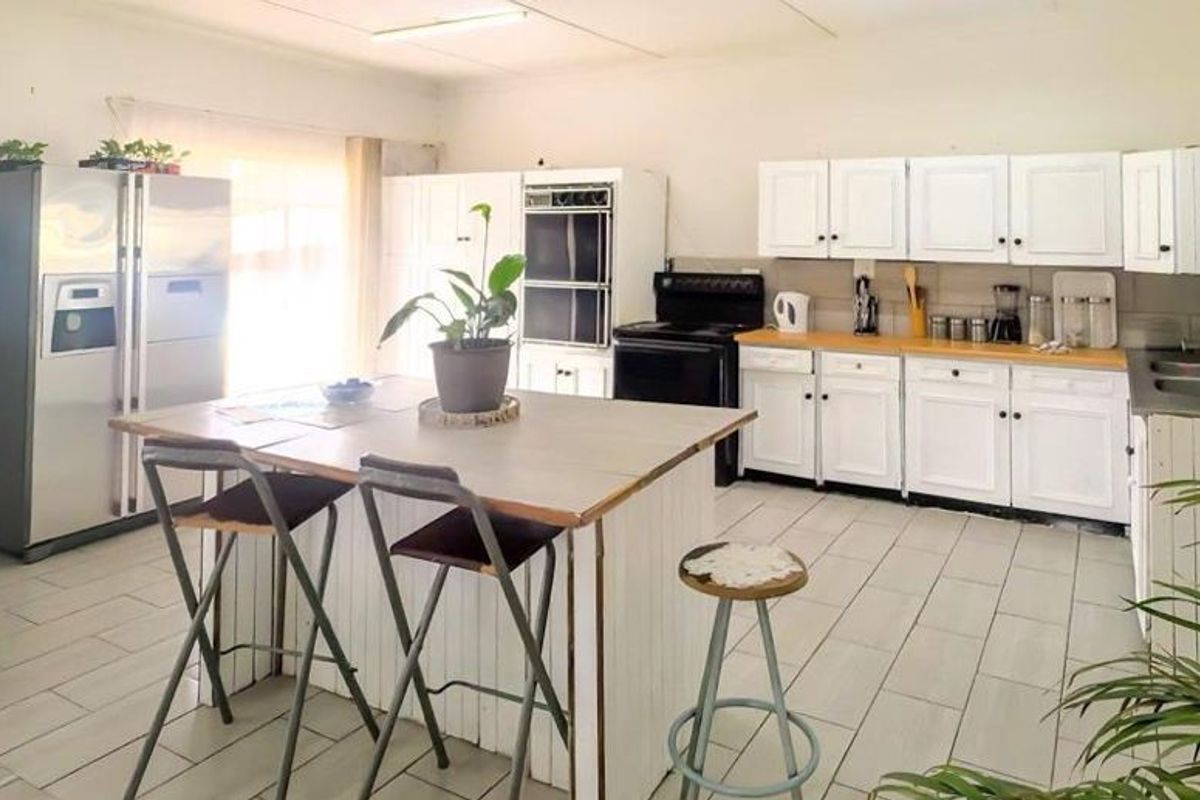 Spacious kitchen featuring white cabinetry, a central island, double wall oven, and tiled flooring, offering a functional layout with ample storage space.