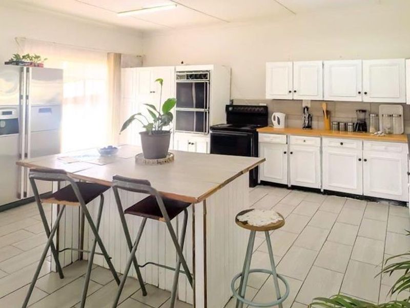 Spacious kitchen featuring white cabinetry, a central island, double wall oven, and tiled flooring, offering a functional layout with ample storage space.