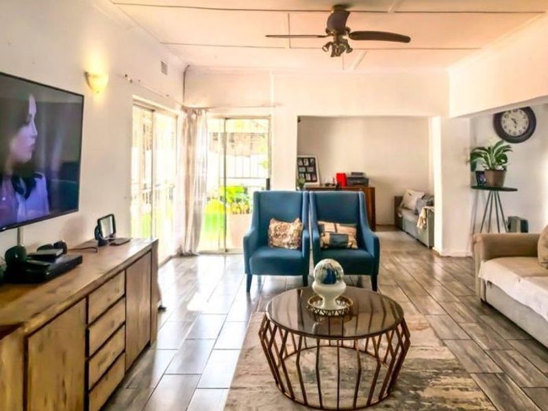 Spacious living room featuring tiled flooring, a ceiling fan, and large sliding glass doors providing natural light and access to the outdoor area.