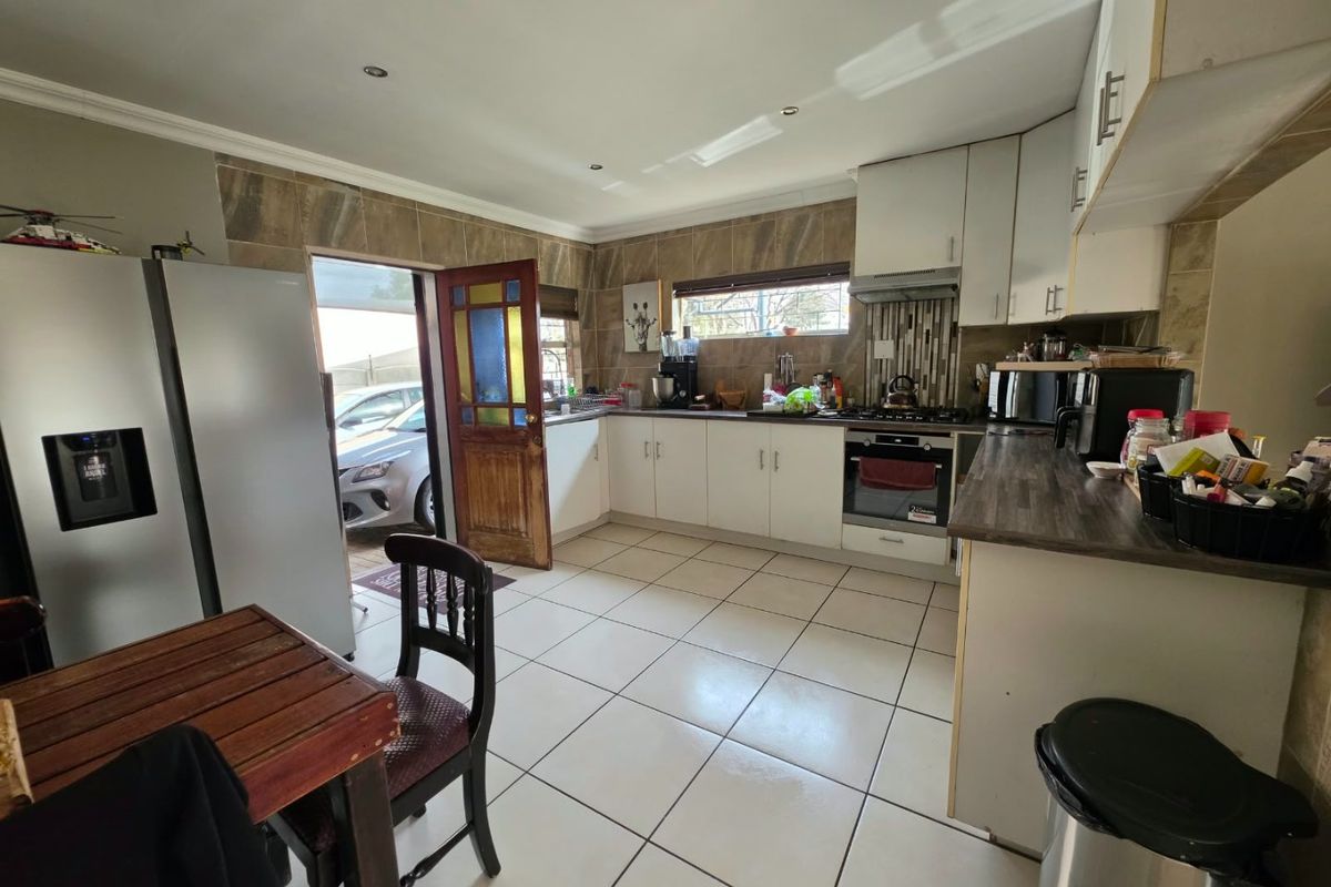 Functional kitchen featuring white cabinetry, tiled backsplash, built-in oven, hob, and extractor fan, with direct access to the exterior.