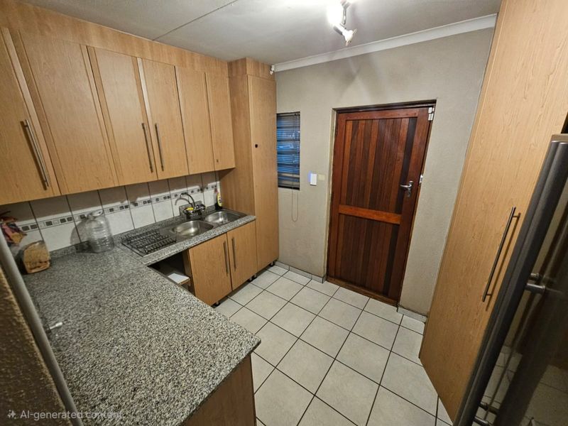 A functional scullery area featuring laminate cabinetry, granite countertops, a double basin sink, and tiled flooring with direct access to an exterior door.