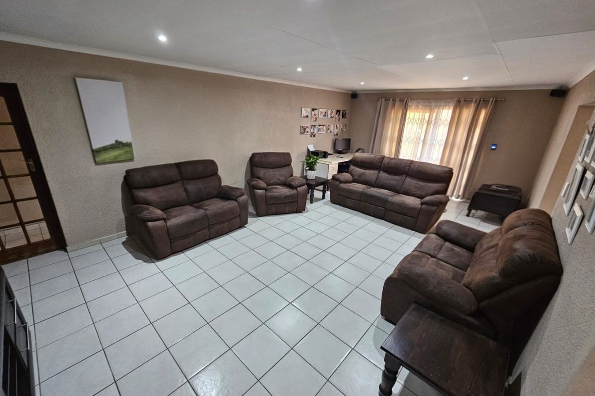 Spacious living room featuring neutral wall tones, ceramic tiled flooring, and recessed downlighting, providing a comfortable and functional family area.