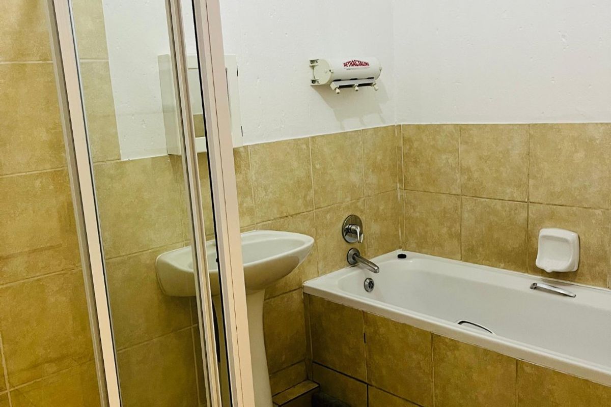 A functional bathroom featuring a pedestal basin, a bathtub with chrome fixtures, and a separate shower enclosure with tiled finishes throughout.