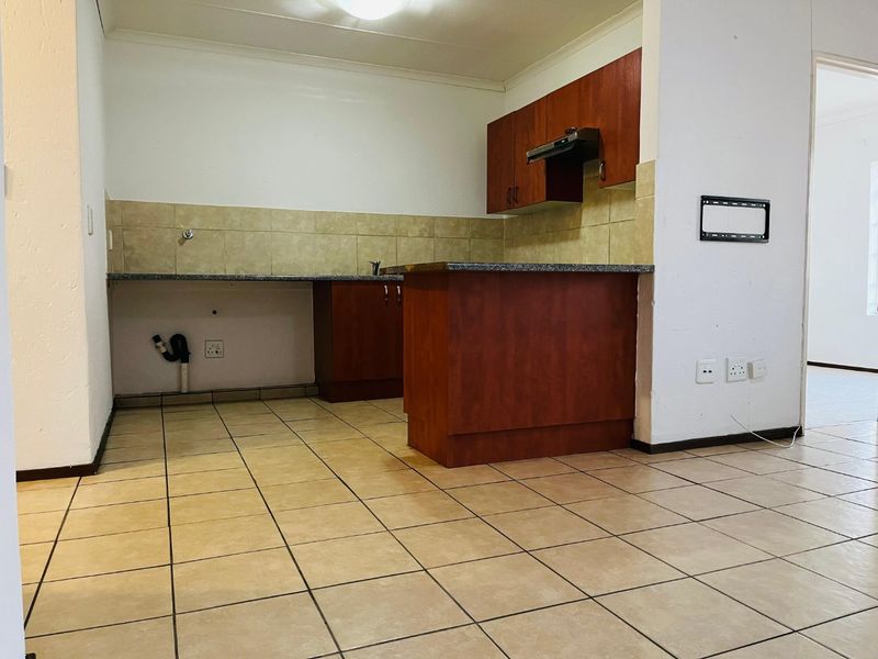 A functional kitchen featuring built-in wooden cabinetry, granite countertops, a tiled backsplash, and dedicated plumbing connections for appliances.