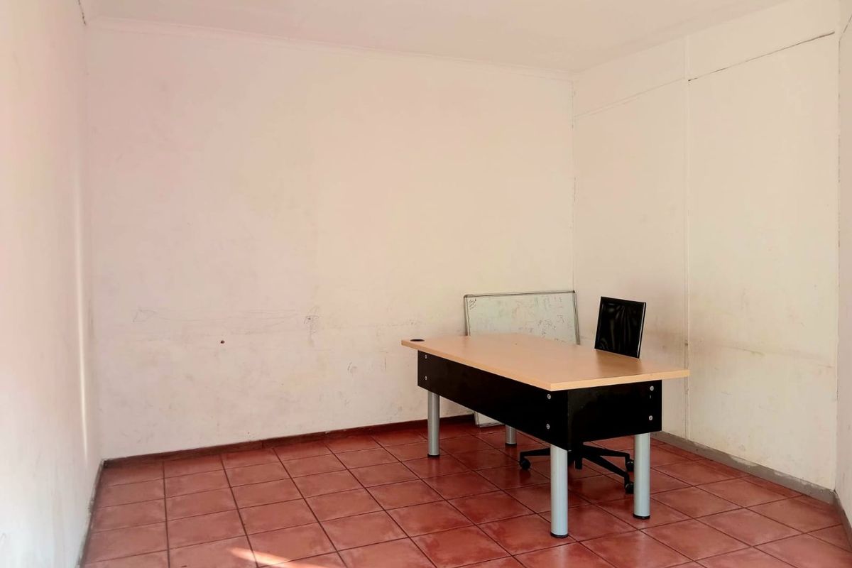 A small, vacant office space featuring ceramic tile flooring and plain white walls, suitable for a professional workspace or private study.
