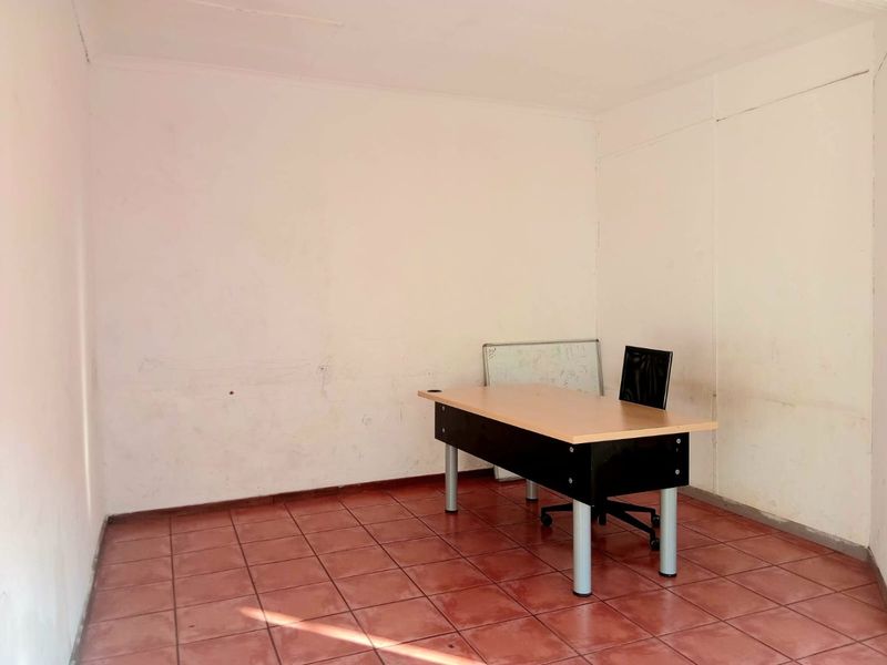 A small, vacant office space featuring ceramic tile flooring and plain white walls, suitable for a professional workspace or private study.
