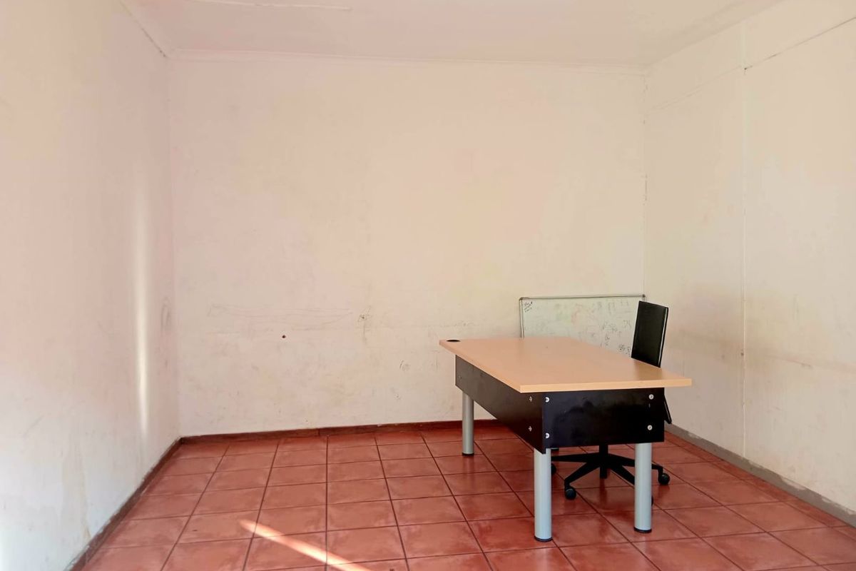 A vacant office space featuring ceramic tile flooring and plain walls, suitable for a professional workspace setup.
