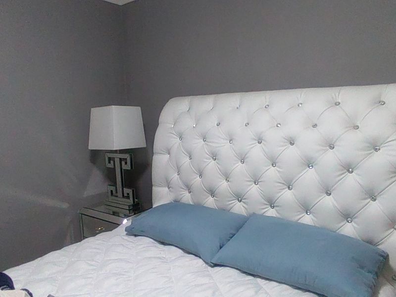 A bedroom featuring grey painted walls and a tufted white headboard.