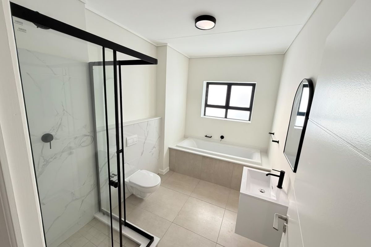 Modern bathroom featuring a walk-in shower with black-framed glass, a built-in bathtub, wall-mounted toilet, and a sleek vanity basin with contemporary black fixtures.