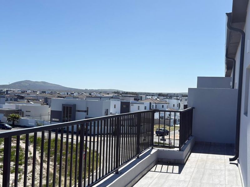 A modern, tiled balcony featuring a secure metal balustrade and offering expansive views of the surrounding residential neighborhood.