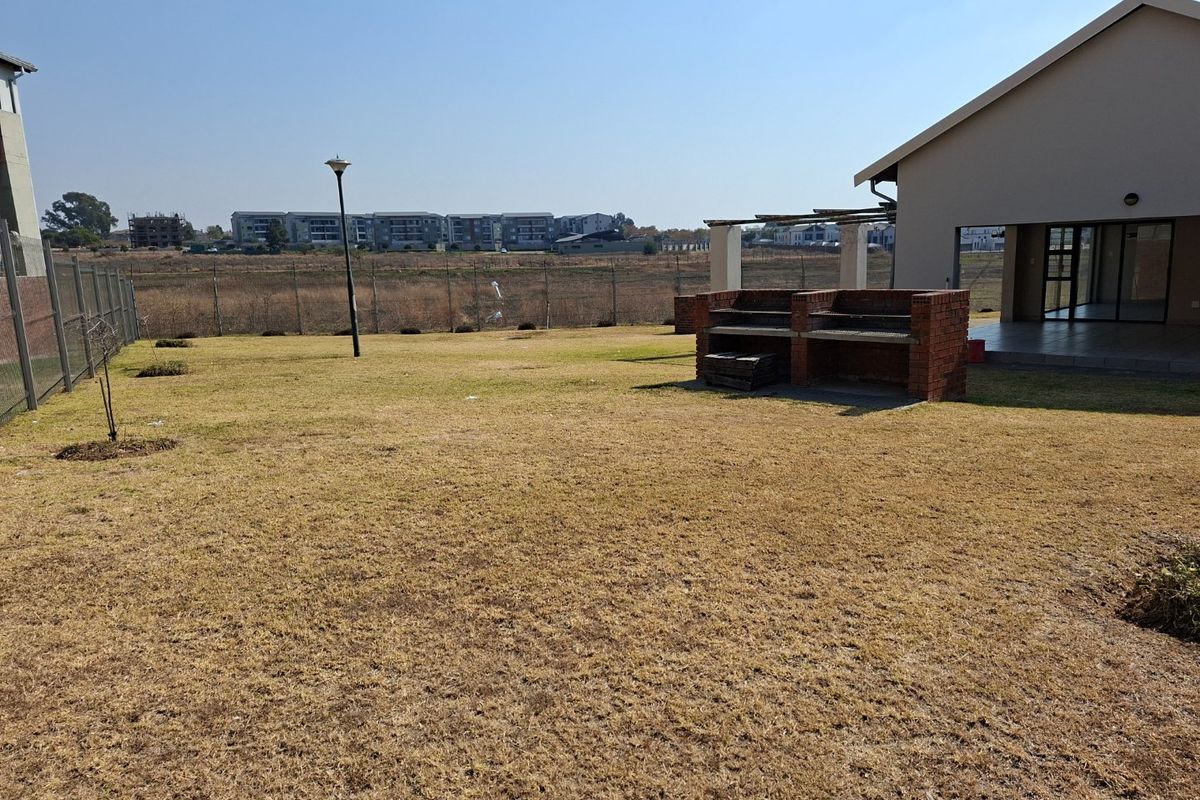 Spacious rear garden featuring a built-in brick braai area and a covered patio, overlooking the surrounding estate.