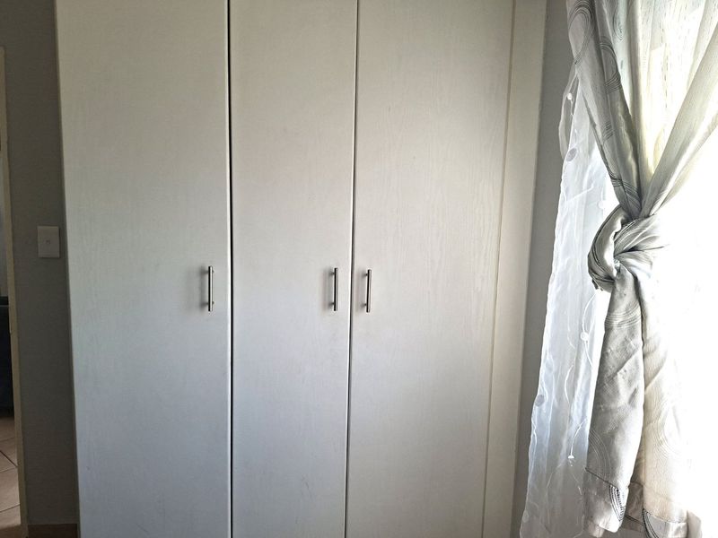 A bedroom featuring a clean, white built-in wardrobe with modern metal handles.