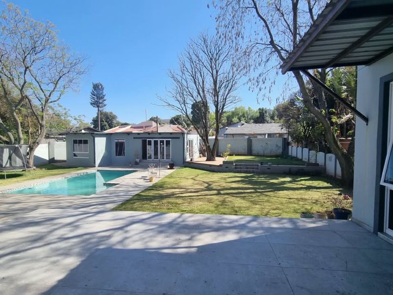 Spacious rear garden featuring a swimming pool, paved patio area, and well-maintained lawn, providing an ideal space for outdoor relaxation and entertainment.