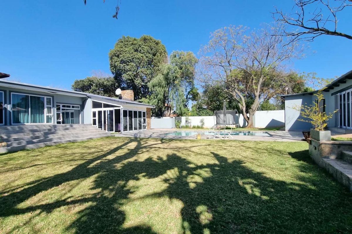 Spacious rear garden featuring a swimming pool, paved patio area, and direct access to the main house via large sliding glass doors.