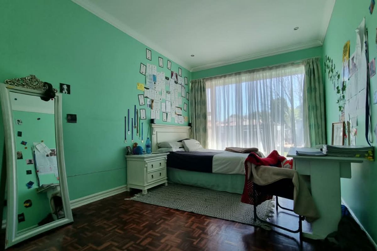 A bedroom featuring parquet flooring, coved cornicing, and a large window allowing natural light.